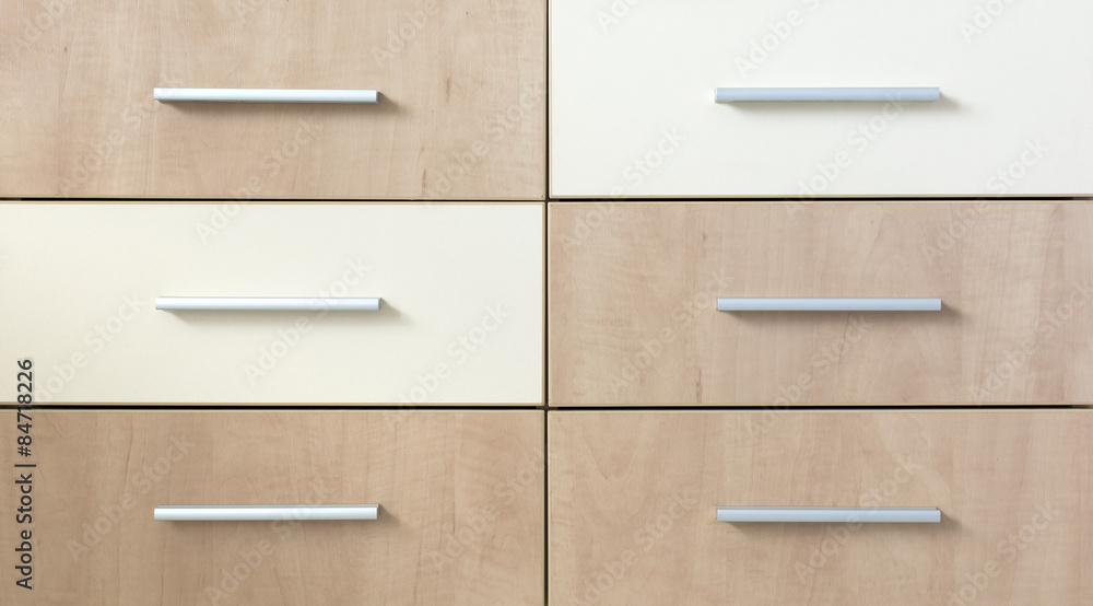 Cropped cabinet with six symmetric drawers. Abstract image of side furniture cabinet business desk wooden box two light and four dark with modern looking grey metallic handles Cropped cabinet with six symmetric drawers. Abstract image of side furniture cabinet business desk wooden box two light and four dark with modern looking grey metallic handles