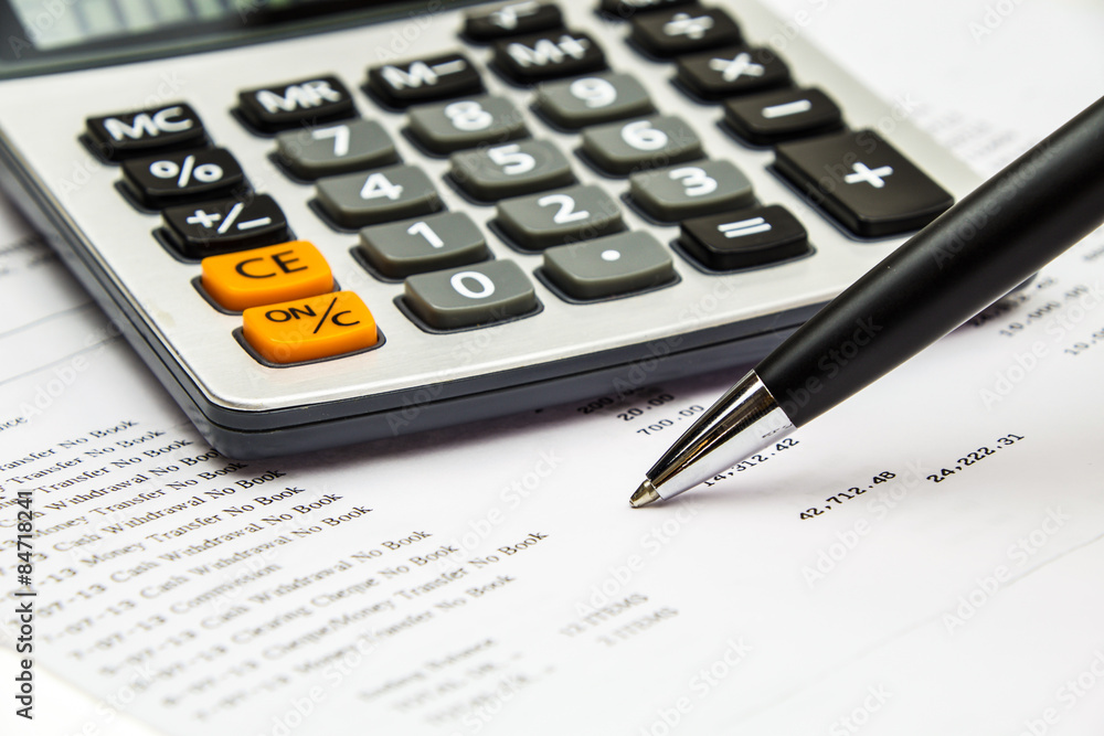 Pen point on bank statement with calculator Pen point on bank statement with calculator