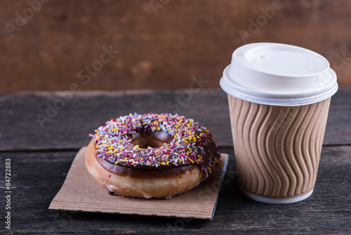 fresh artisan donut and take away coffee, wooden background