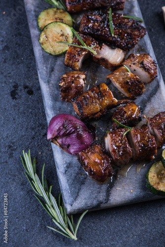 Grilled pork belly slices on marble board and veggies from above