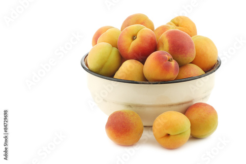 Fresh colorful apricots in an enamel bowl on a white background