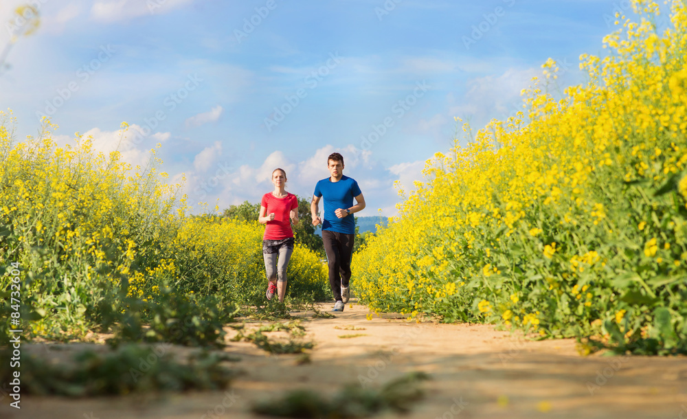 Obraz premium Beautiful young runners outside in canola field