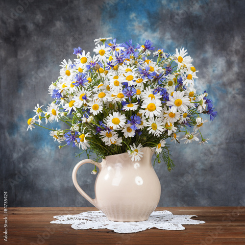 Camomile and cornflowers in a basket on table