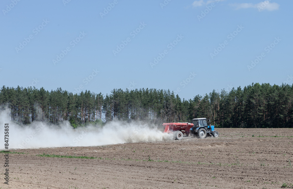 Fototapeta premium The tractor is spraying fertilizer in a field