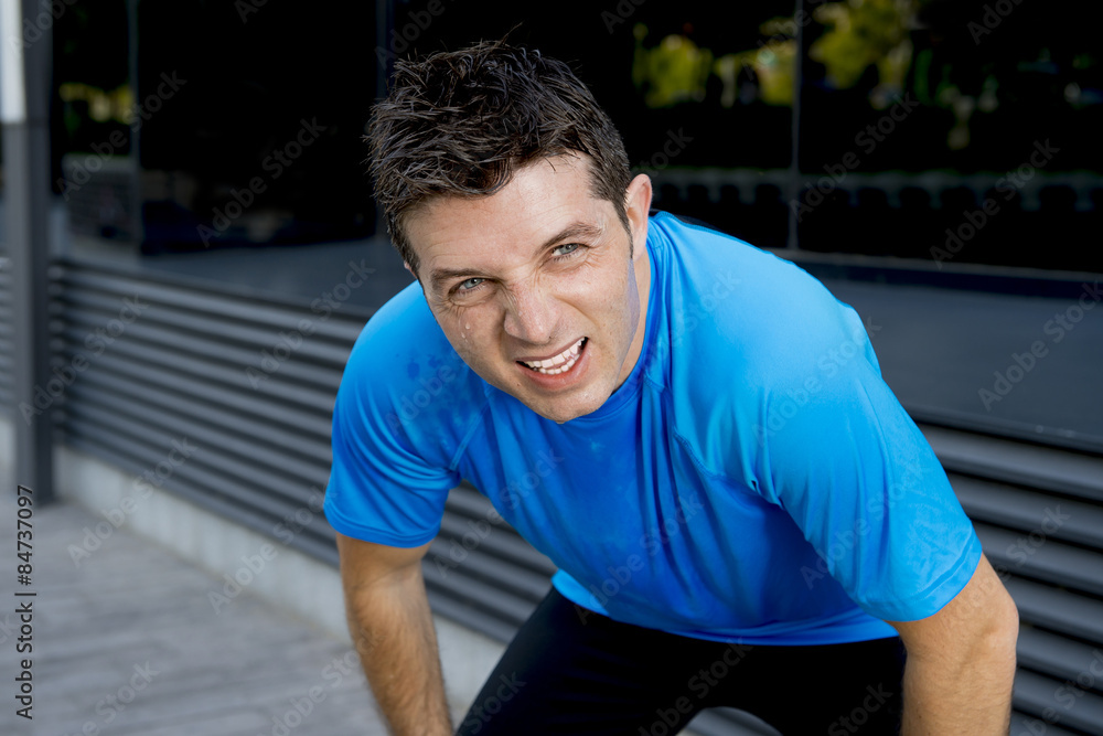 young attractive man leaning exhausted after running session sweating taking a break to recover in urban street young attractive man leaning exhausted after running session sweating taking a break to recover in urban street