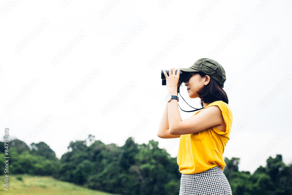 Women and binoculars in hands on green meadow with focus on a binocular