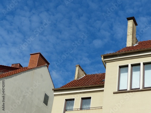 Rotbraune Dächer mit Schornstein einer Häuserzeile in Beige und Naturfarben vor blauem Himmel im Sonnenschein in der Paulinenstraße in Detmold in Ostwestfalen-Lippe