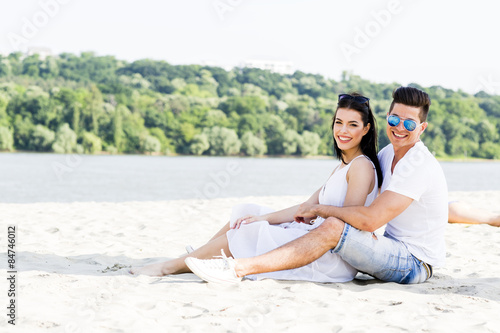 Romantic young couple sitting at a beach © NDABCREATIVITY