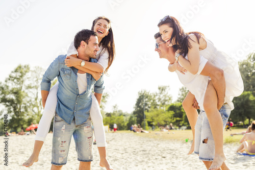 Group of young happy people carrying women on a sandy beach