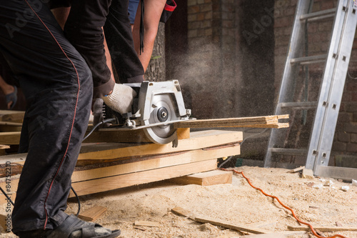 Men Using Power Saw to Cut Planks of Wood