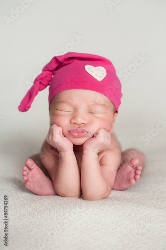 Newborn Baby Girl Wearing a Pink, Top Knot Cap