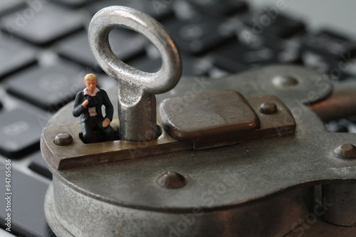 Internet security concept-miniature businessman stand on old key