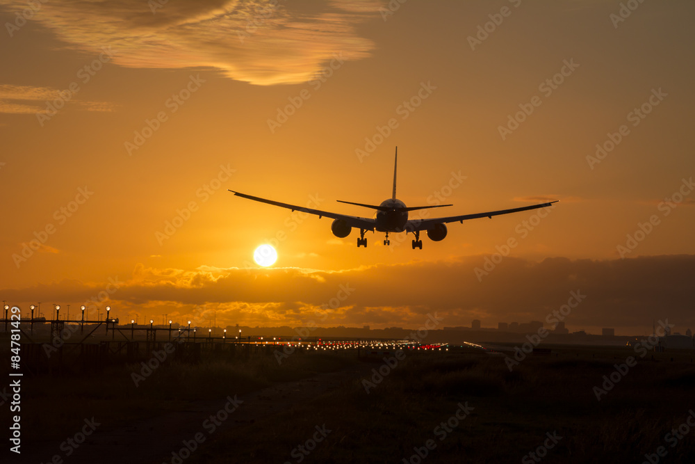 Airplane is landing during a beautiful cloudy sunrise.