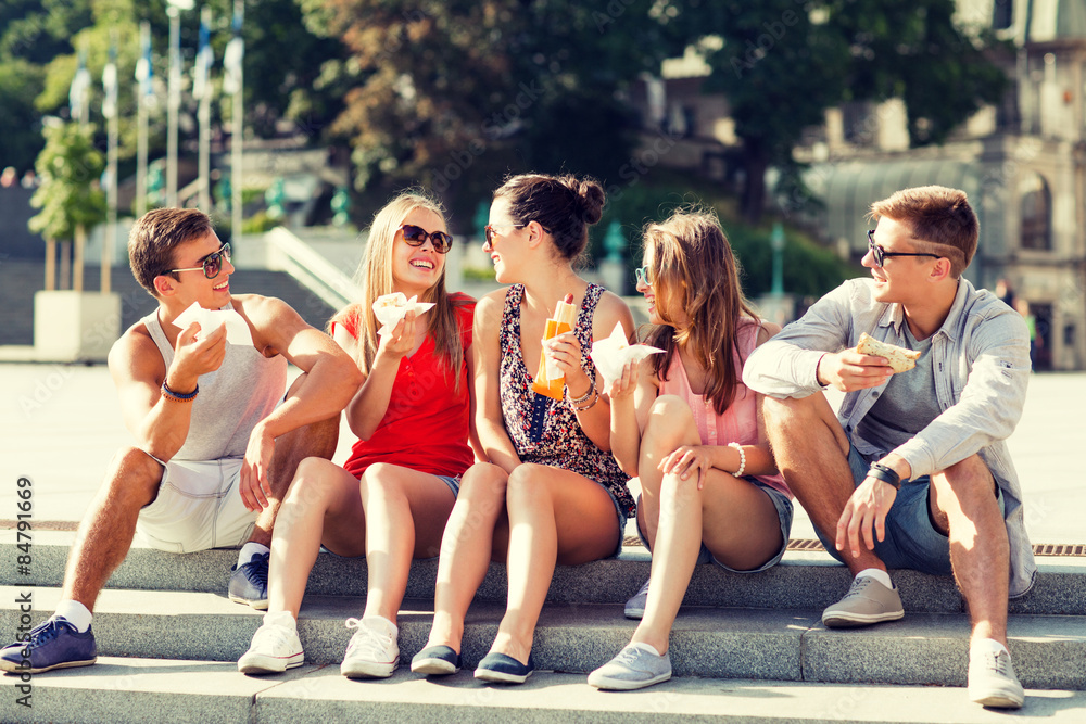 group of smiling friends sitting on city square group of smiling friends sitting on city square