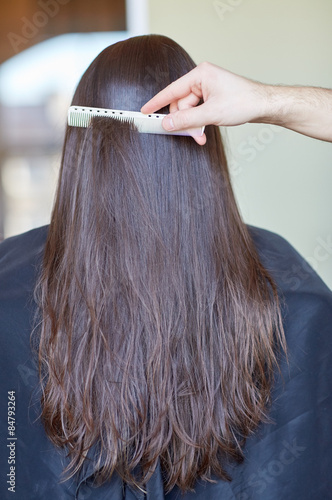 hand with comb combing woman hair at salon