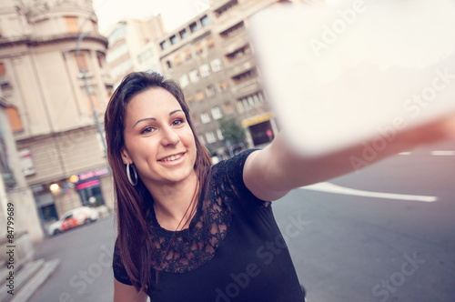 Fotografie Happy beautiful young woman taking a selfie with her smart phone.