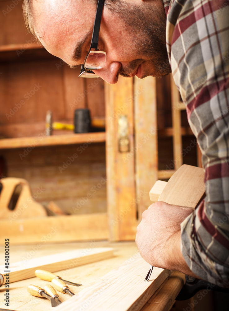 Young carpenter working with a chisel and carving tools in his workshop Young carpenter working with a chisel and carving tools in his workshop