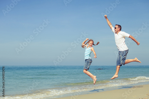 Father and daughter playing on the beach at the day time.