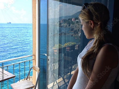 Ragazza guarda dal balcone a picco sul mare 