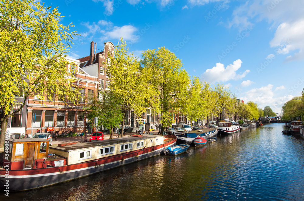 Φωτογραφία Amsterdam canal with boats along the bank of the river during the sunny day, Netherlands