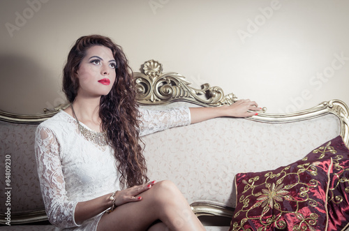 Pretty model girl sitting on victorian sofa posing for camera photo