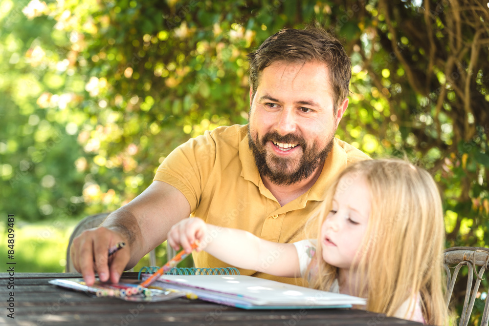 Father with daughter in the garden at the table, doing homework Father with daughter in the garden at the table, doing homework