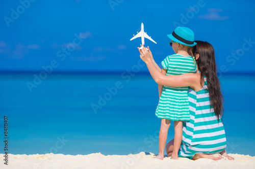 Little girl and mom with white miniature of airplane at beach