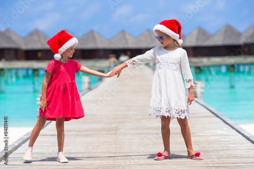 Little adorable girls in Santa hats during beach vacation at