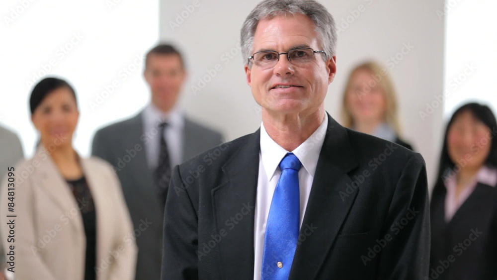 Portrait of mature business man with co-workers in background Portrait of mature business man with co-workers in background