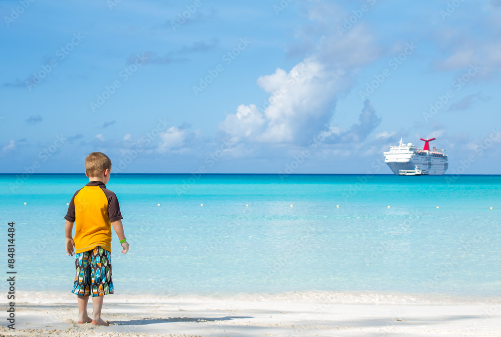 Little boy on the shore looking at the ship