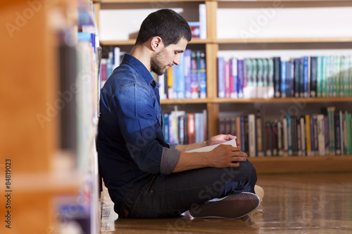 Male student reading a book at the library