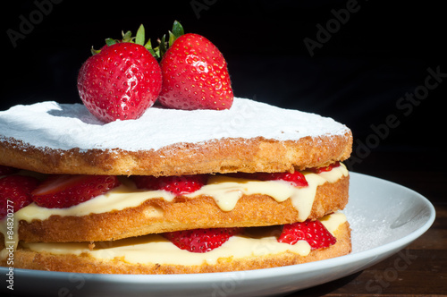 A homemade Swedish strawberry layer cake filled with fresh strawberries and a custard cream. Topped with fresh strawberries and dusted with icing sugar.