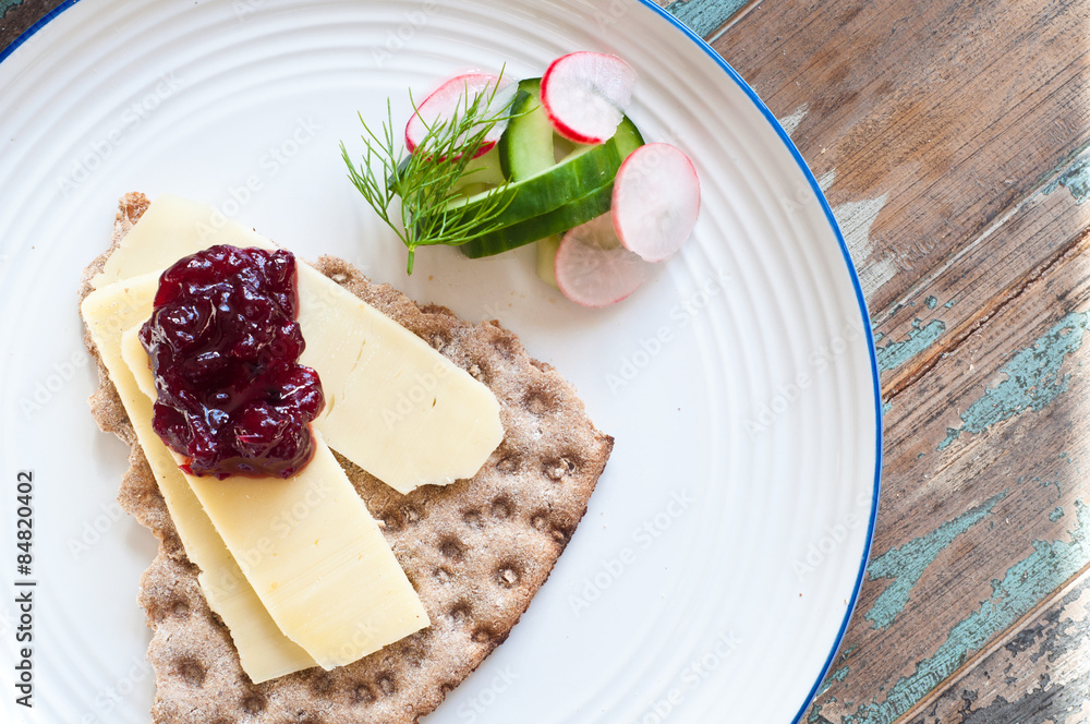 Scandinavian crisp bread topped with cheese and lingonerry jam served with a salad of cucumber, radish and dill.