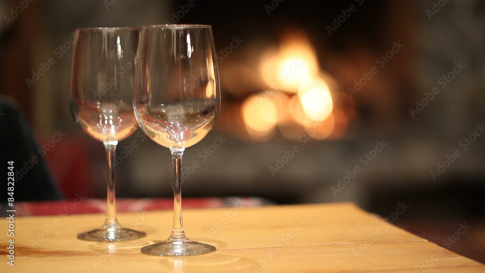 Pouring glasses of wine by fireplace Pouring glasses of wine by fireplace