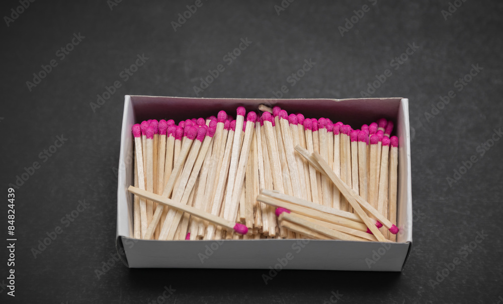 Closeup view of many pink matchsticks in carton box on dark grey background Closeup view of many pink matchsticks in carton box on dark grey background