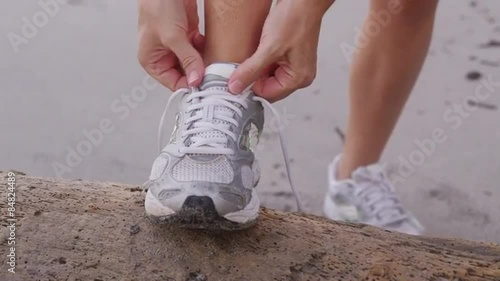 Closeup of woman tying running shoe at beach