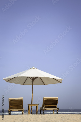 Tropical beach scenery with parasol and chairs   