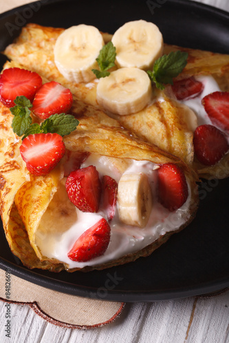 crepes with strawberries, bananas and cream close-up. Vertical 