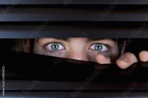 Foto Young looking behind a blind, with eyes wide open.