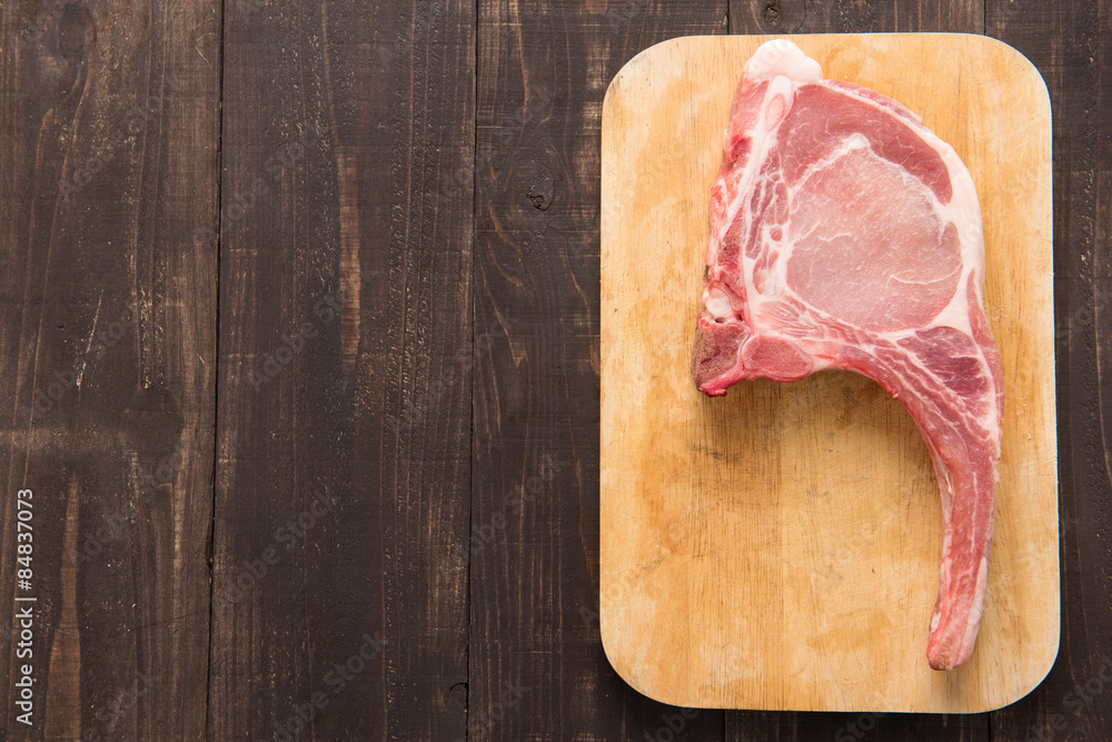 Fresh pork chops or cutlets on wooden background.