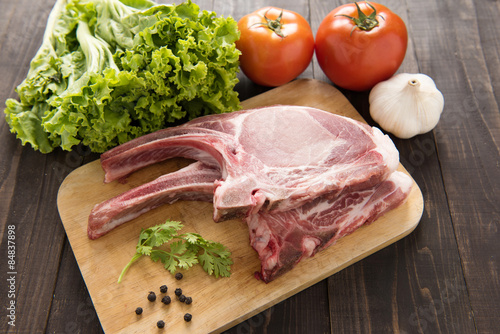 Fresh Raw Pork Chops and vegetable on wooden background.