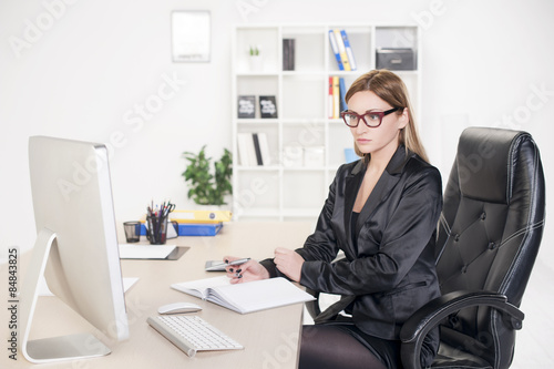 Business woman in her mid thirties sits at a desk in front of a computer