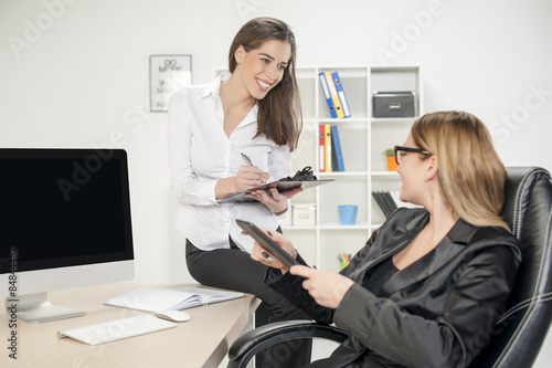 Business women in her mid thirties sits at a desk in front of a computer