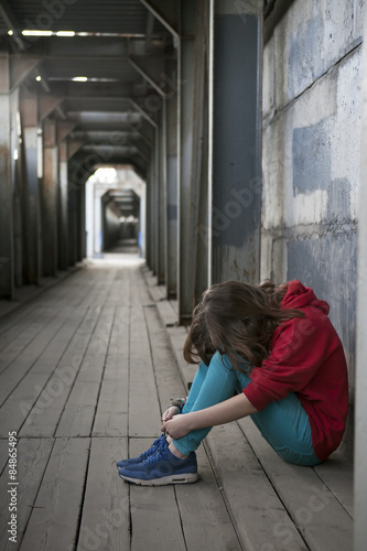 Depressed teenage girl in red hoody with hands over her face