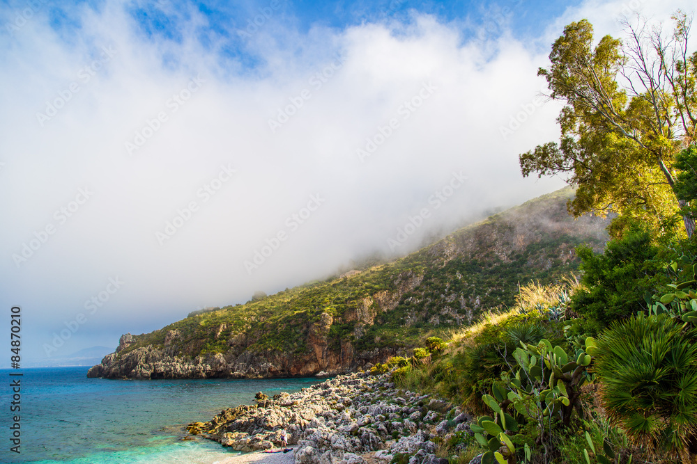 Rocky coastline with low clouds in Sicily