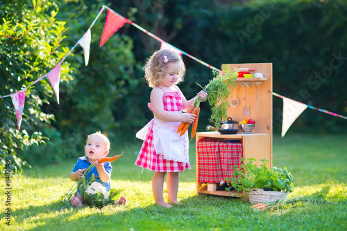 Obraz na plátně Kids playing with a toy kitchen in a summer garden