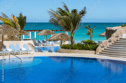 Amazing  inviting view of modern stylish swimming pool against tranquil azure ocean and blue sky background © Vit