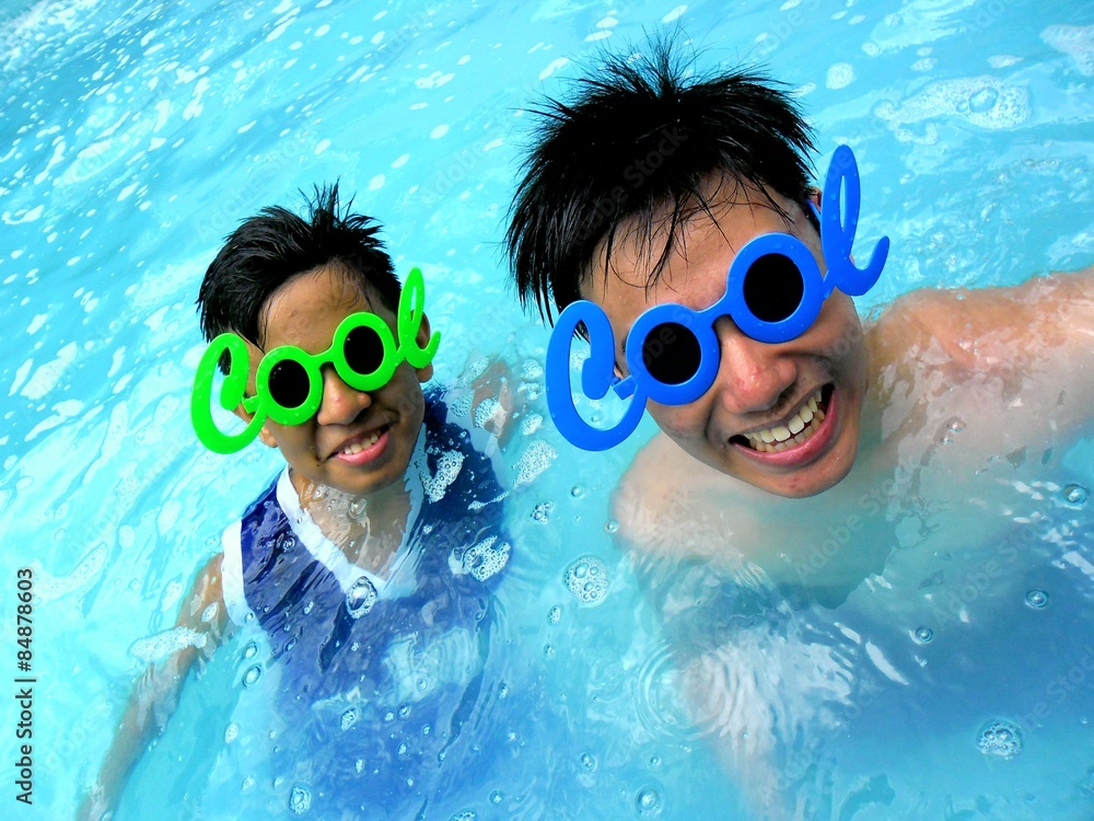 Naklejka premium Two young boys in a swimming pool with funny shades