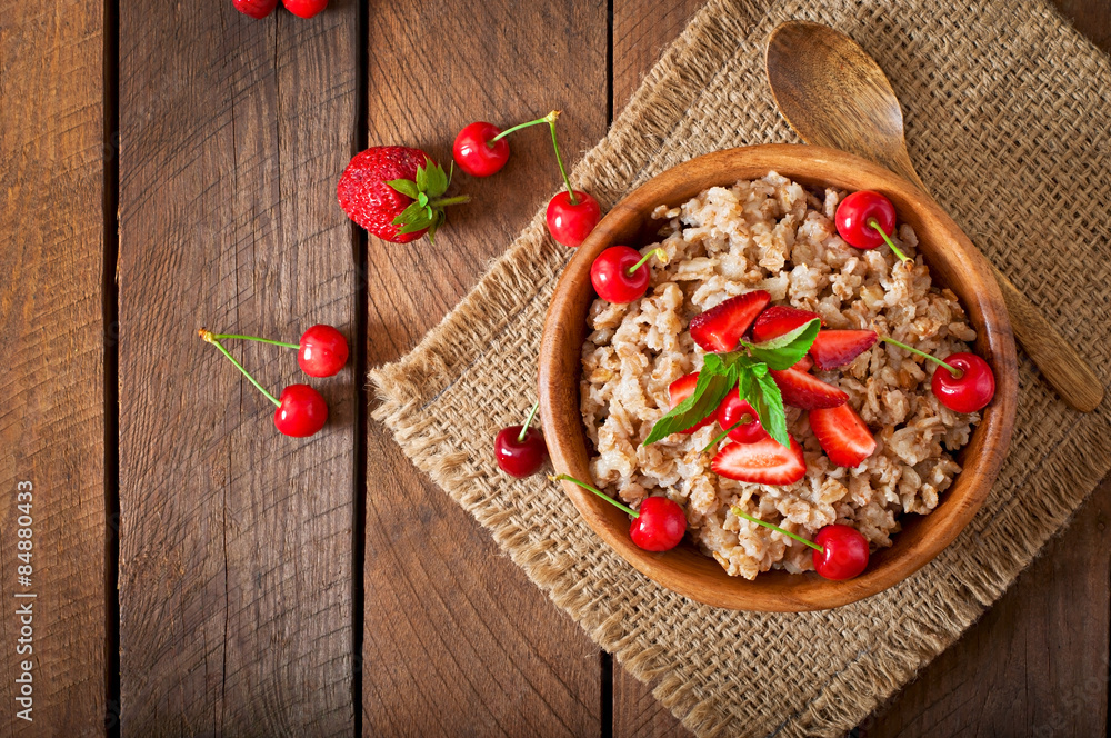 Oatmeal porridge with berries in a wooden bowl Oatmeal porridge with berries in a wooden bowl