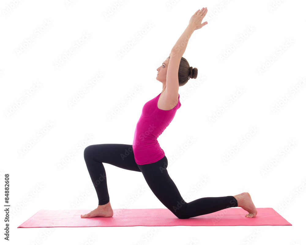 young beautiful slim woman standing on pink mat in yoga pose iso